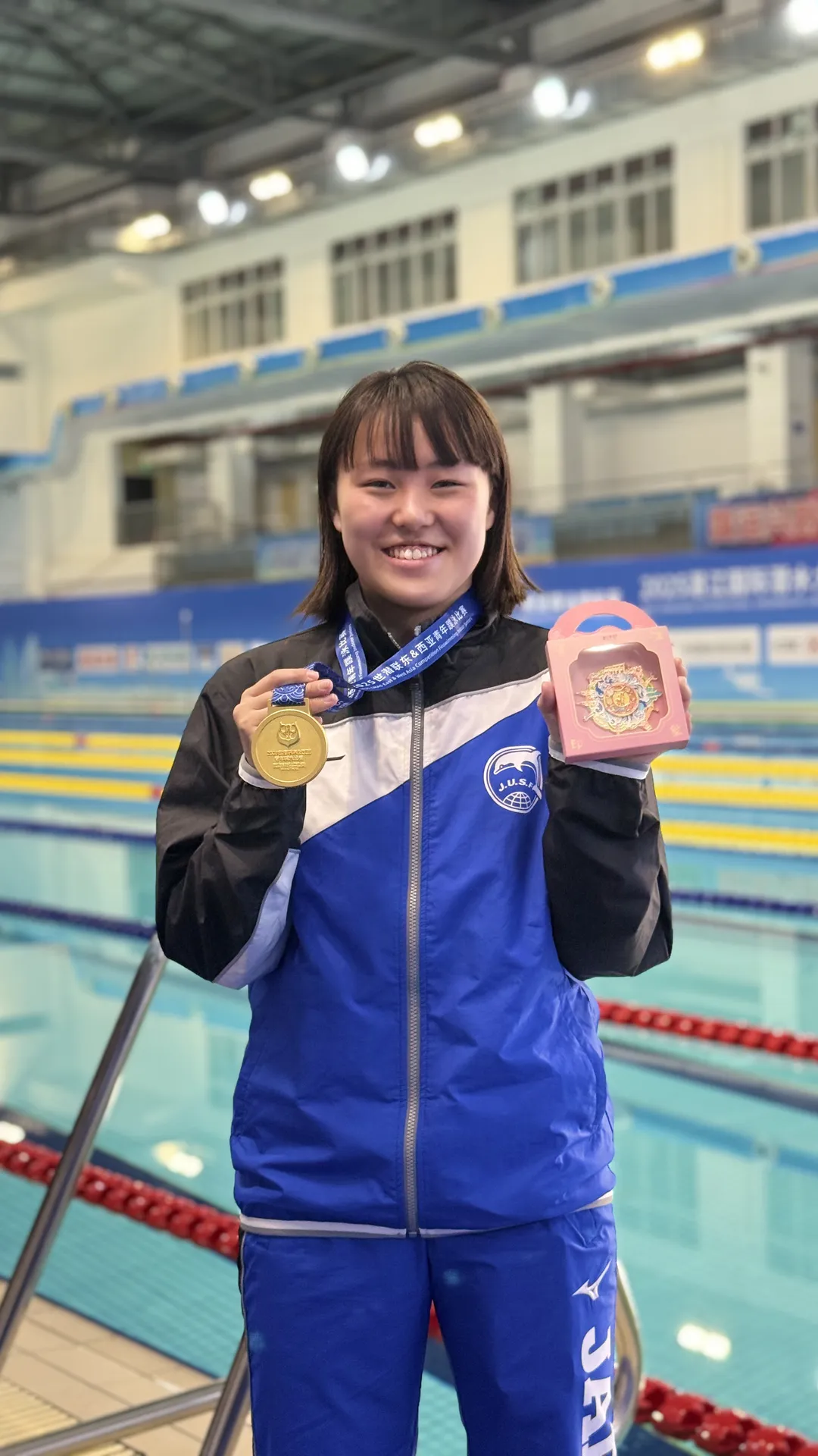 日本代表フィンスイミング秋本咲陽選手がプールサイドでメダルを掲げる記念写真