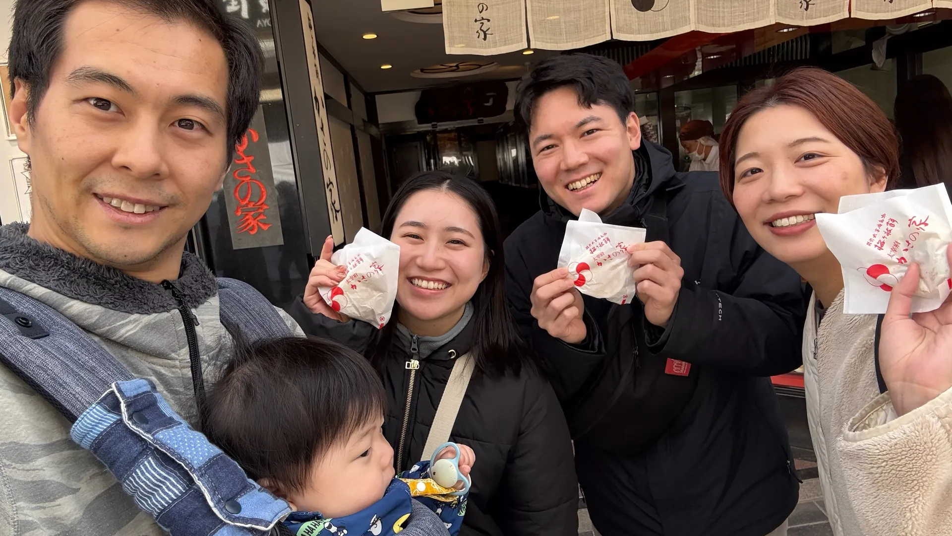 AQUA FinDメンバーが太宰府のお店前で和菓子を持ち笑顔で記念撮影する様子