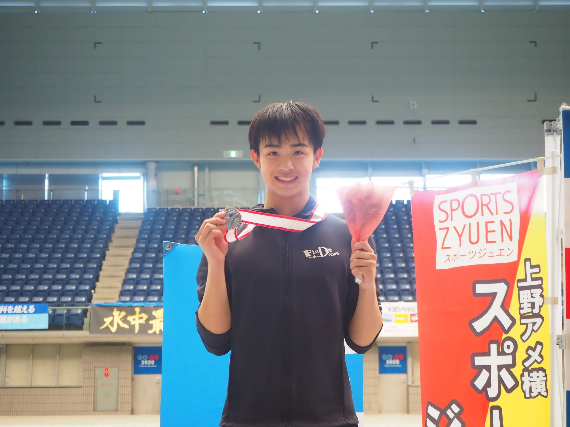 AQUA FinDの選手がフィンスイミング大会でメダルと花束を掲げて笑顔で記念撮影