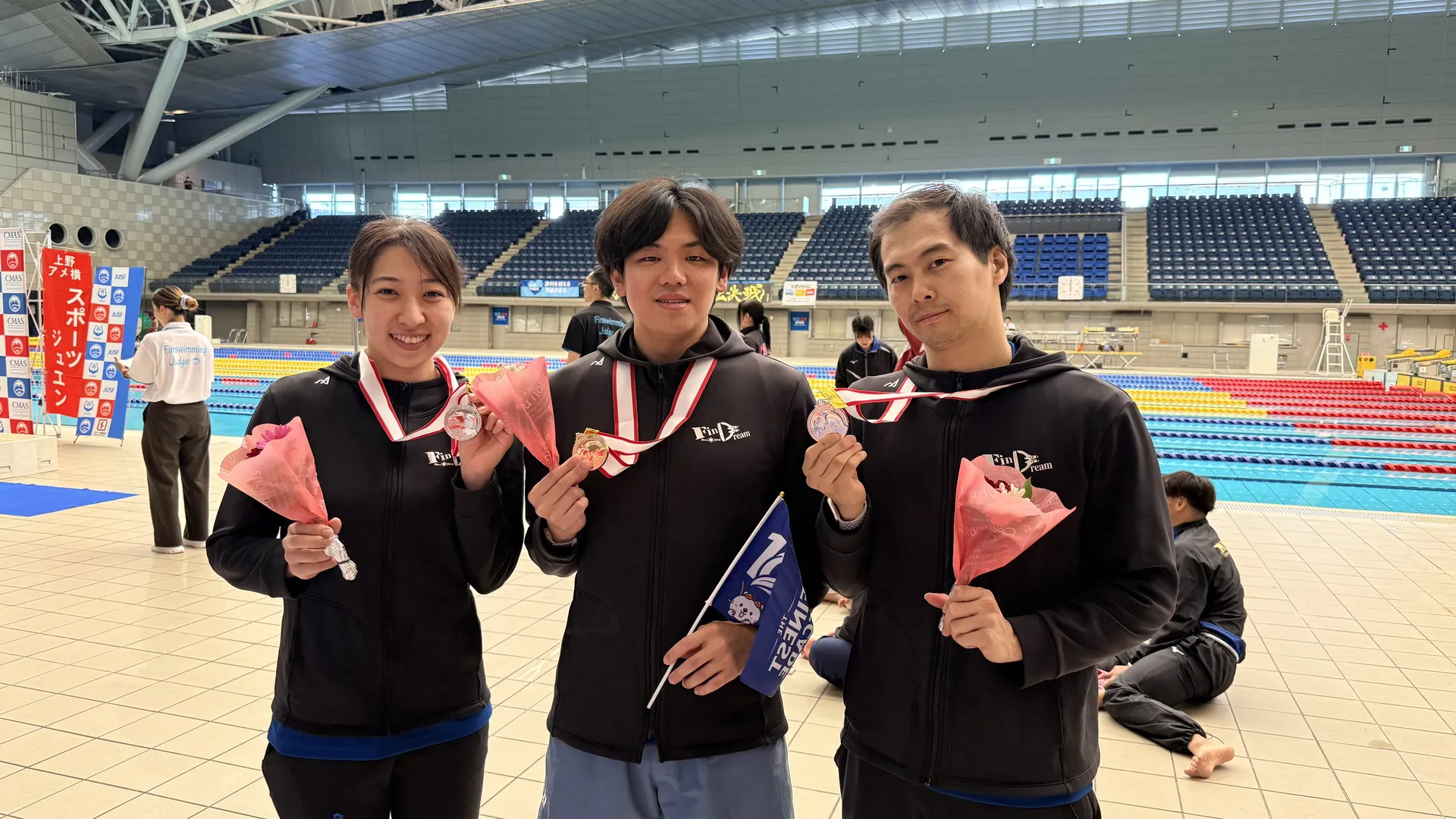 AQUA FinDの選手3名がフィンスイミング大会でメダルと花束を掲げて記念撮影
